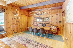 Cozy dining area with a wooden table and chairs, surrounded by exposed beams and a stone wall.