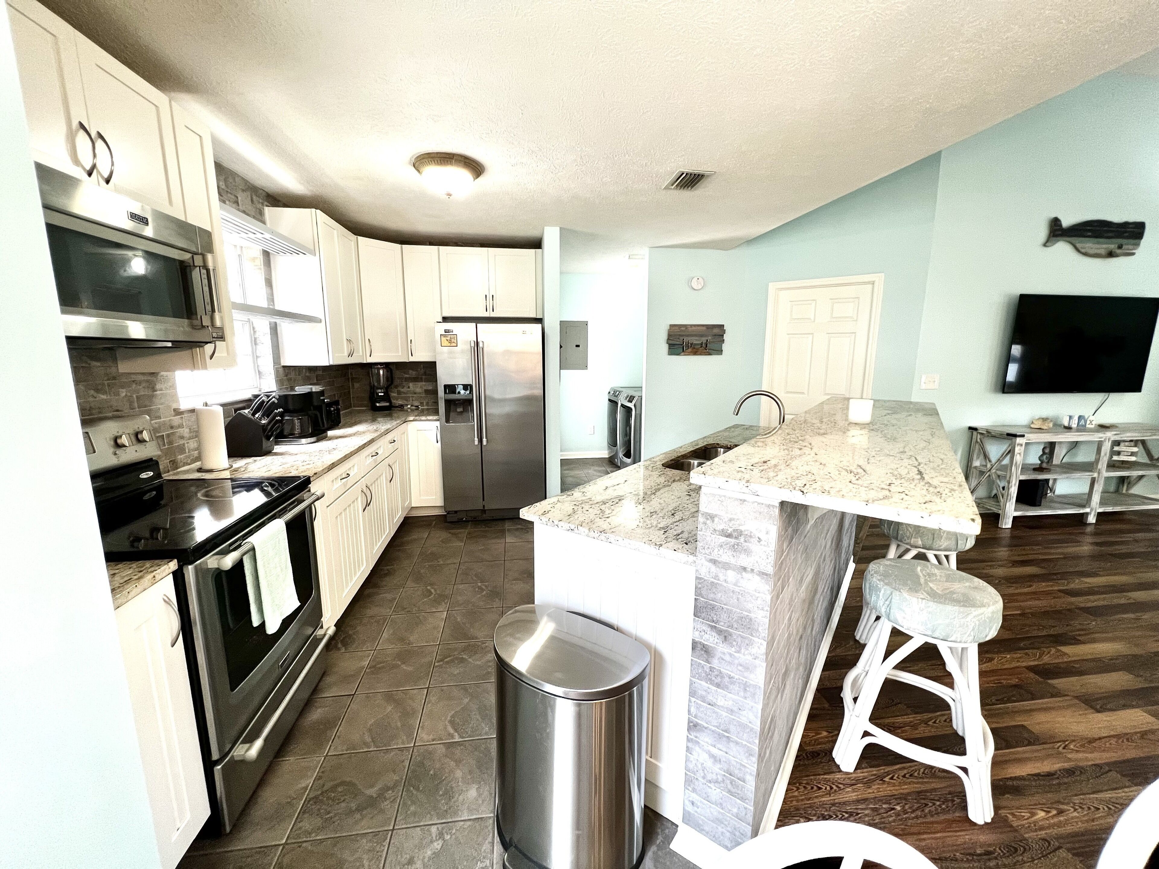 A modern kitchen with stainless steel appliances, a marble countertop, and a wooden dining area.