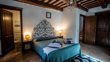 Une chambre avec un plafond en bois, un lit recouvert d’une couverture verte, deux lampes de chevet, une table de chevet et une armoire en bois.