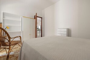 Une chambre à coucher avec un lit, une chaise, une armoire et un miroir.