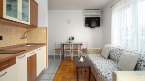A compact kitchen with a sink, cabinets, and a dining area with chairs and a table. - FUNTANA Apartments BUDINJAŠ  2, FREE BIKES (FUNTANA)