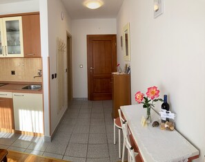 A kitchen with a sink, cabinets, and a wooden door. There is a table with chairs and a vase with flowers.