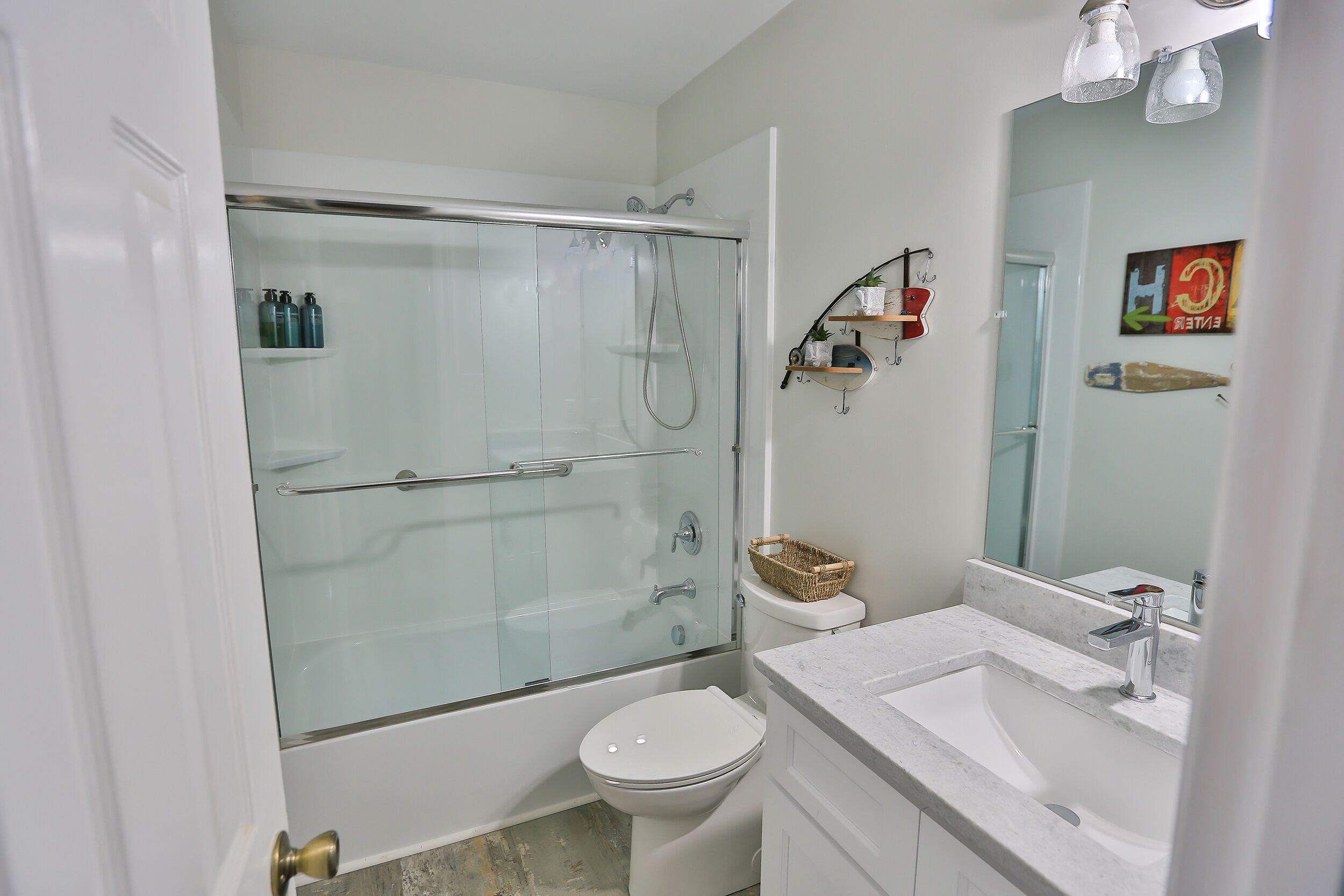 Un baño moderno con ducha de vidrio, inodoro blanco y lavamanos de mármol.