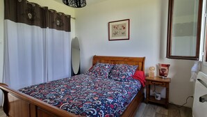 A bedroom with a wooden bed, a nightstand with a lamp, a mirror, and a framed picture on the wall. - Maison d'Hérré ⭐⭐⭐Independent accommodation in main residence with swimming pool  (ST GIRONS)