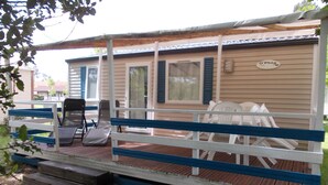 A mobile home with a porch, outdoor seating, and a sign reading "O'Phéa 734". - Mobile home rental (Mimizan)