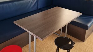 A modern room with a blue sofa, a wooden table, a red stool, and a black chair. - Mobile home rental (Mimizan)