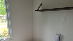 A small, single-room accommodation with a bed, a bench, and a window. - Mobile home rental (Mimizan)