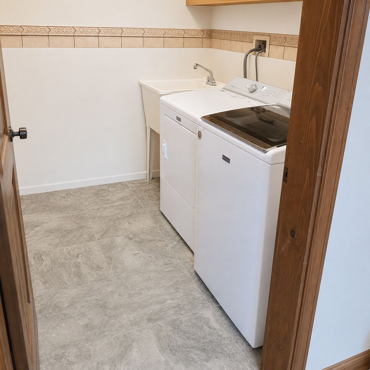 A laundry room with a washing machine, dryer, and sink.