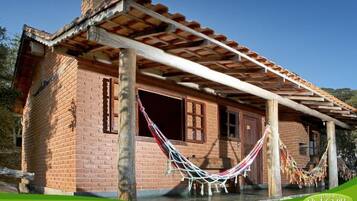 A brick building with a wooden porch and a hammock.