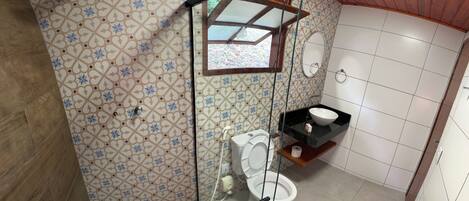 A bathroom with a patterned tile wall, a toilet, a glass-enclosed shower, and a sink with a black countertop.