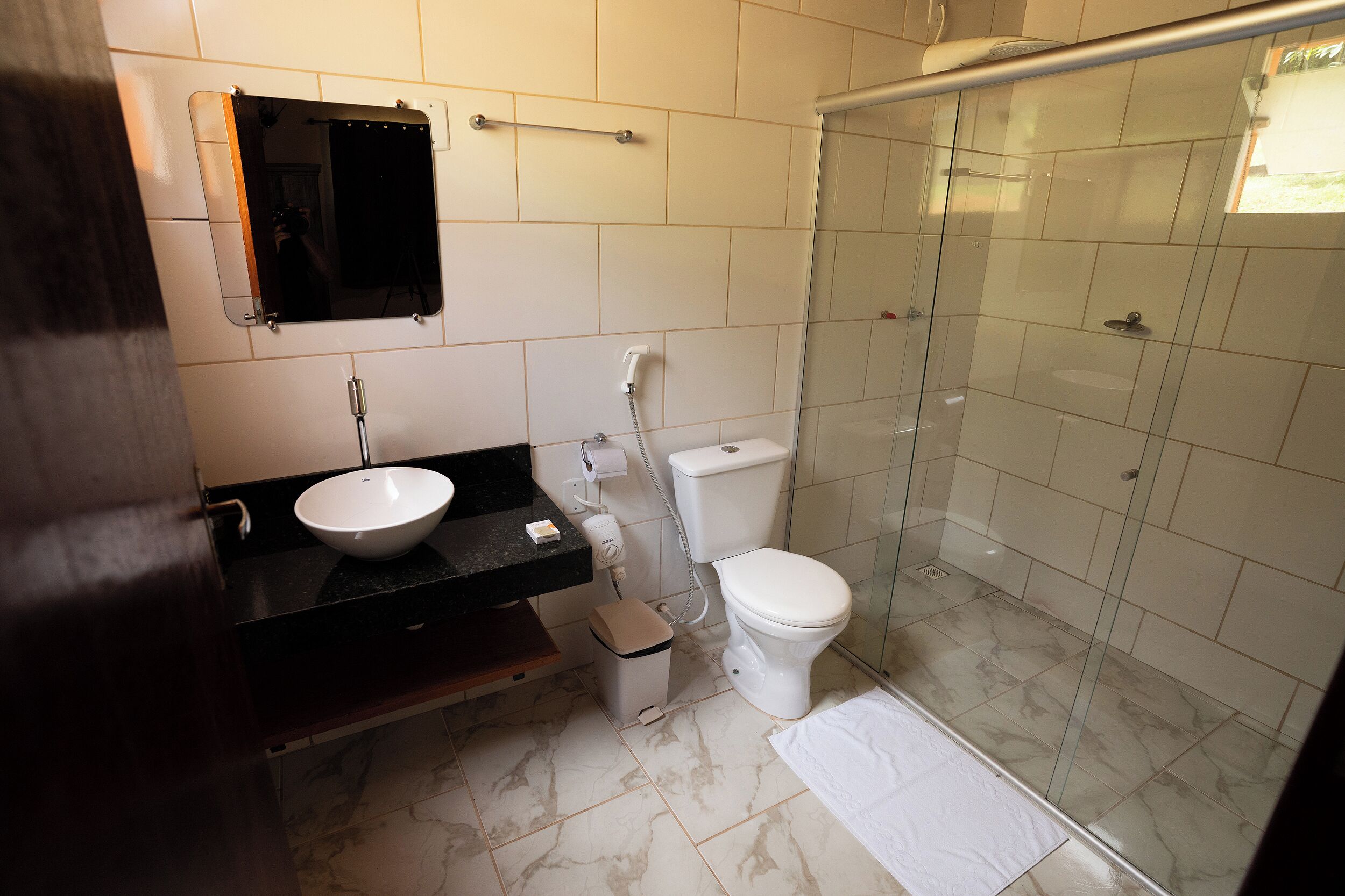 Baño con lavabo, inodoro y cabina de ducha con mampara de vidrio.