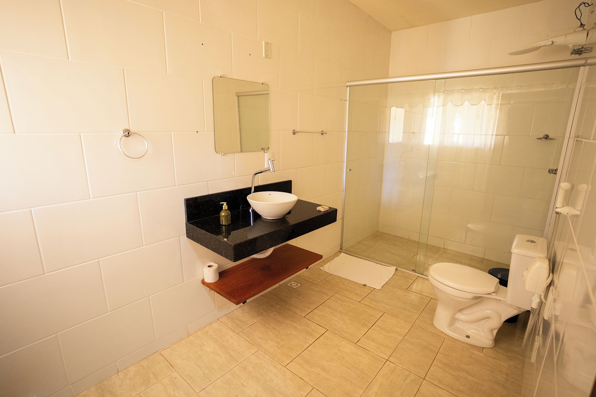 Et badeværelse med vask, spejl, toilet og bruser.