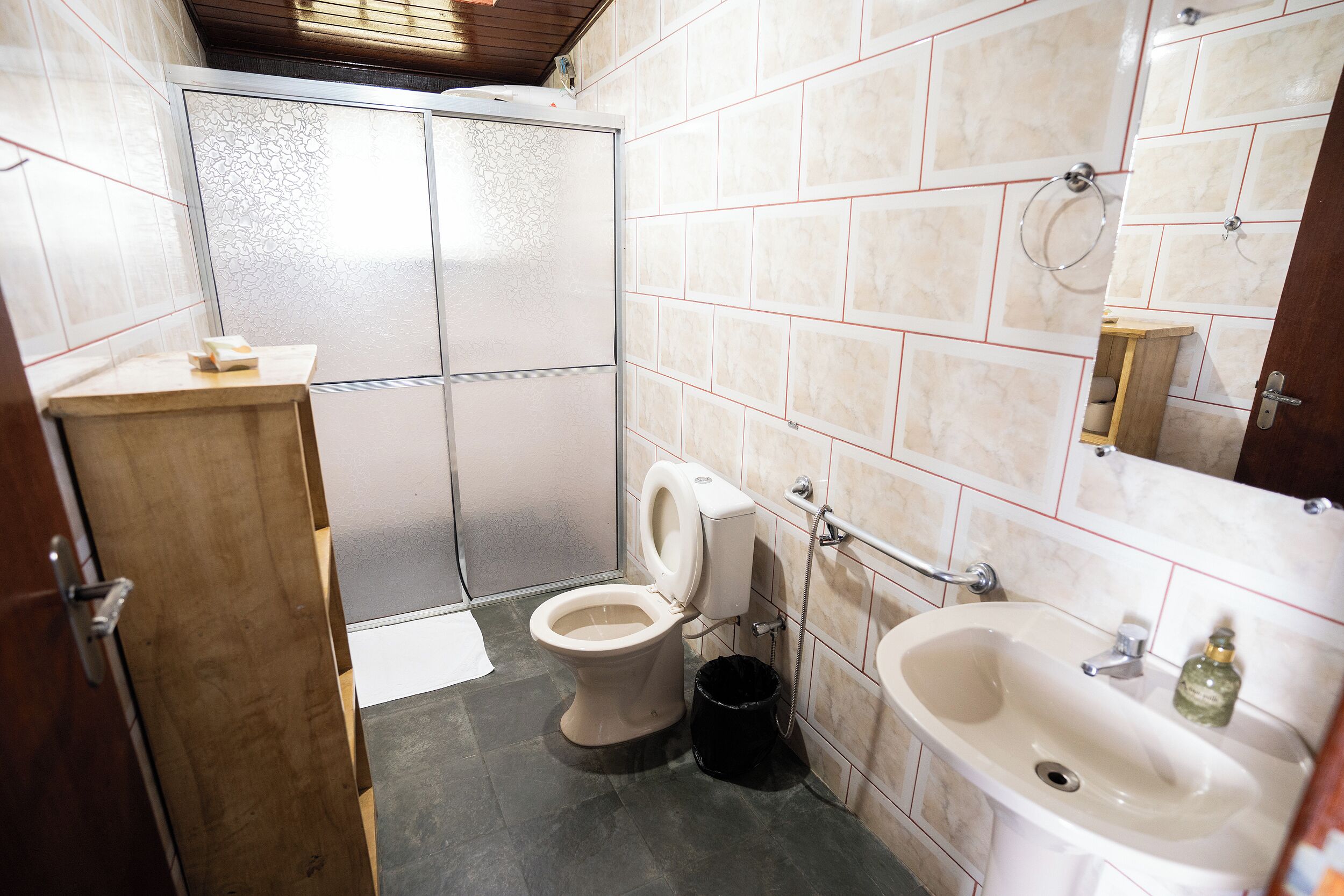 Un baño con inodoro, bidé, lavabo y un armario de madera.
