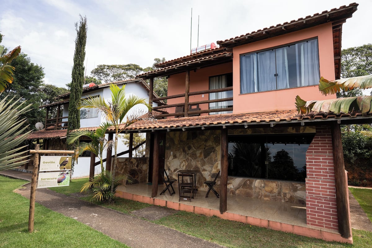 Uma casa de dois andares com varanda, parede de pedra e uma placa.