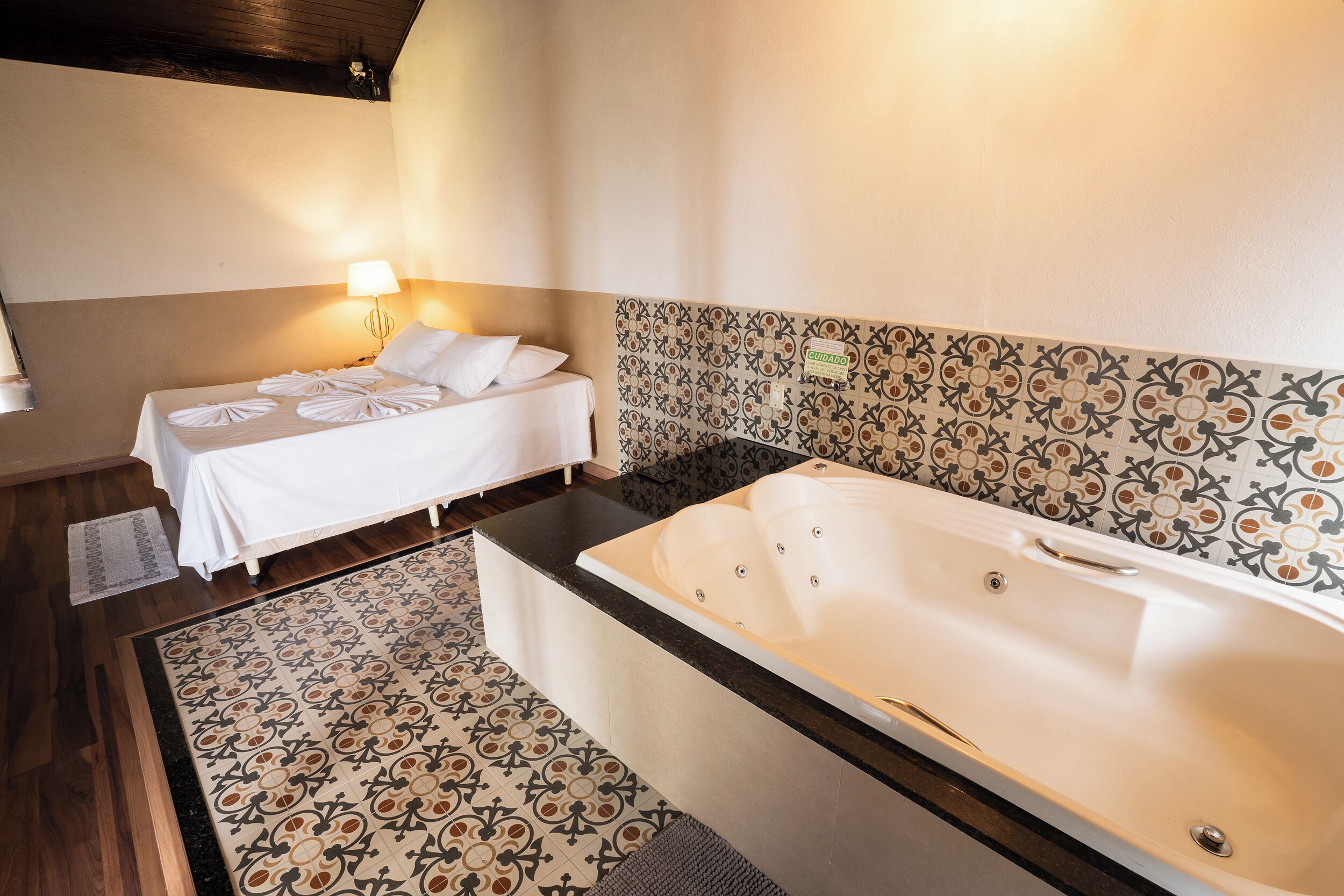 Quarto de hotel com cama, uma banheira grande e parede com padrão.