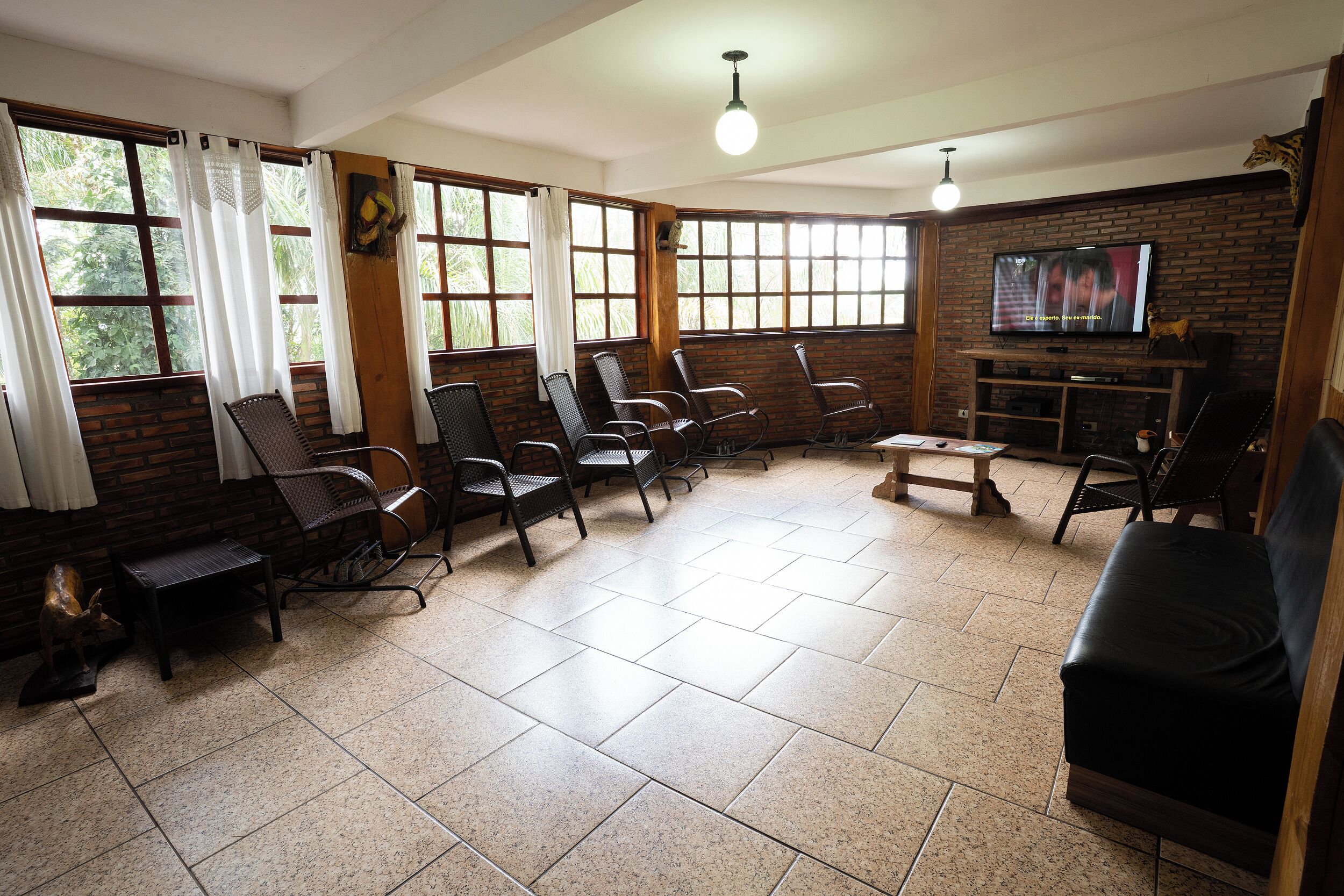 A room with a brick wall, a television, and several chairs.