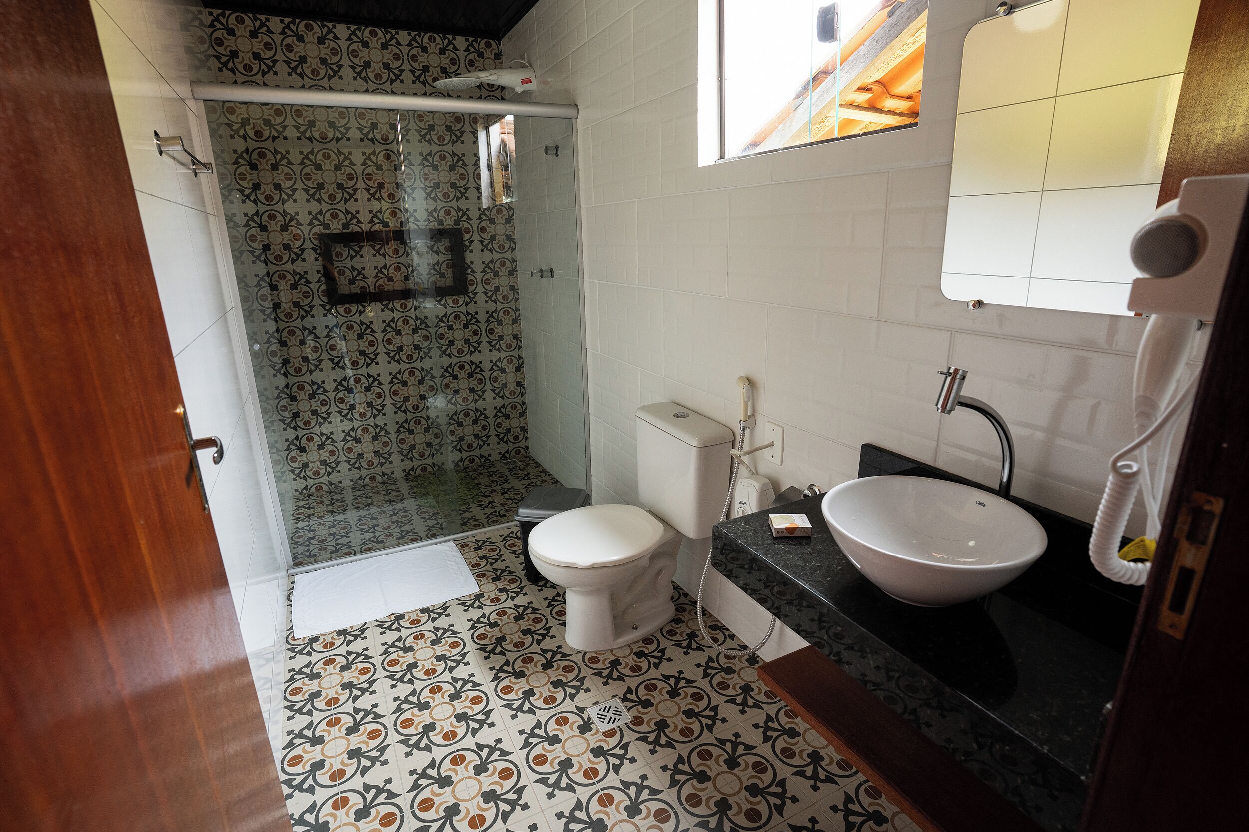 Un bagno con piastrelle a motivi, un WC bianco, un lavandino e uno spazio doccia.