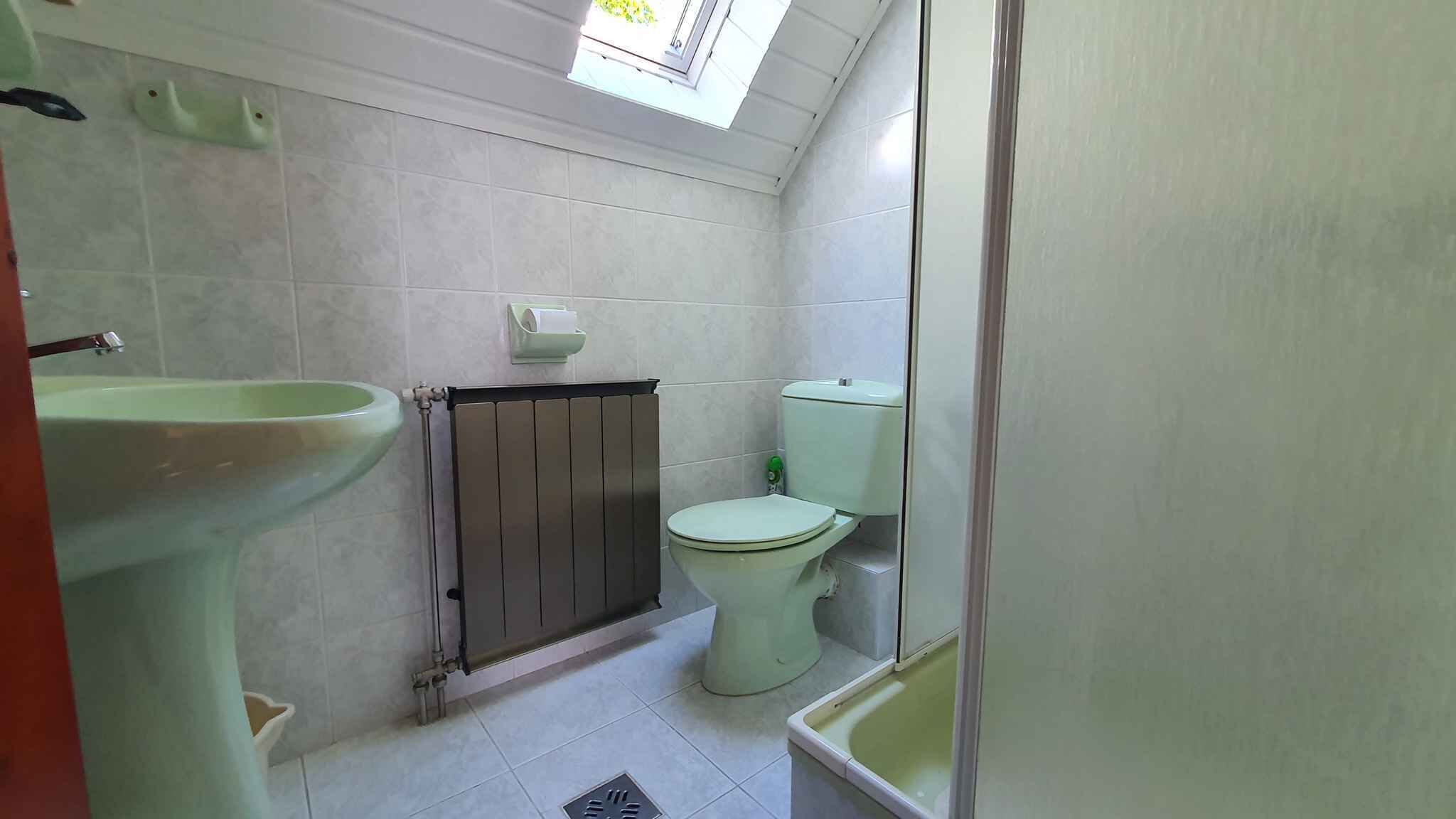 Un baño pequeño y limpio con inodoro, lavabo y ventana sobre el inodoro.