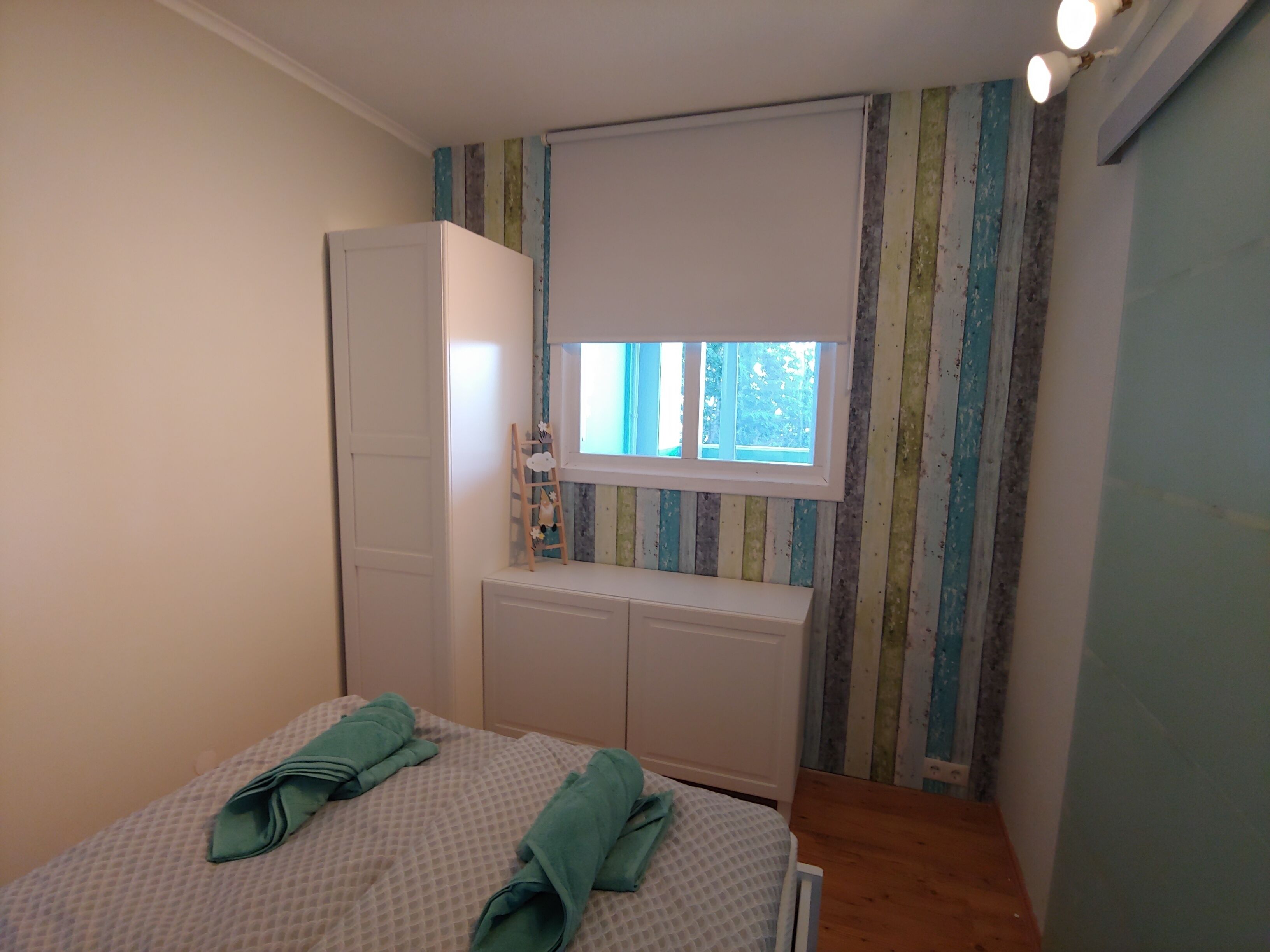 A bedroom with a bed, a wardrobe, a window, and a radiator.