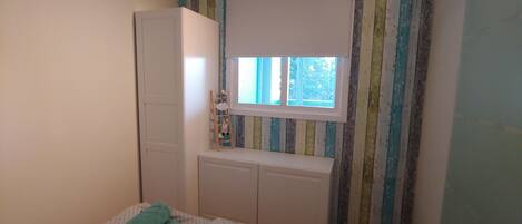 A bedroom with a bed, a wardrobe, a window, and a radiator.
