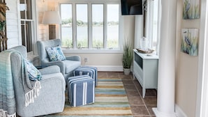 Un salon confortable avec un canapé, un pouf et une vue sur un lac.