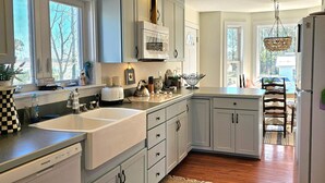 Une cuisine avec des meubles de couleur bleu clair, un réfrigérateur blanc et un plancher en bois.