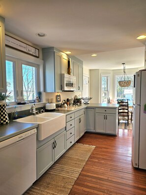 A kitchen with light blue cabinets, a white refrigerator, and a wooden floor.