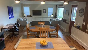 A dining area with a wooden table and chairs, a bowl of lemons, and a kitchen in the background.