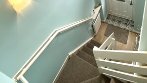 A staircase with a handrail, a light switch, and a door with a window above it. - Well equipped dog friendly cottage ideal for relaxing, walking, cycling, golf (Crieff)