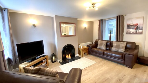 A living room with a fireplace, a sofa, a TV, and a window with curtains. - Well equipped dog friendly cottage ideal for relaxing, walking, cycling, golf (Crieff)