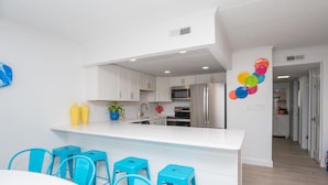 A modern kitchen with white cabinetry, a central island with bar stools, and a microwave. - Beautiful Ocean views, Just renovated 2 bedroom 2 bath Condo, 2 parking spots  (Ocean City)