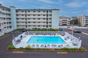 A hotel with a swimming pool surrounded by a white fence, outdoor seating, and a parking area marked "NO PARKING". - Beautiful Ocean views, Just renovated 2 bedroom 2 bath Condo, 2 parking spots (Ocean City)