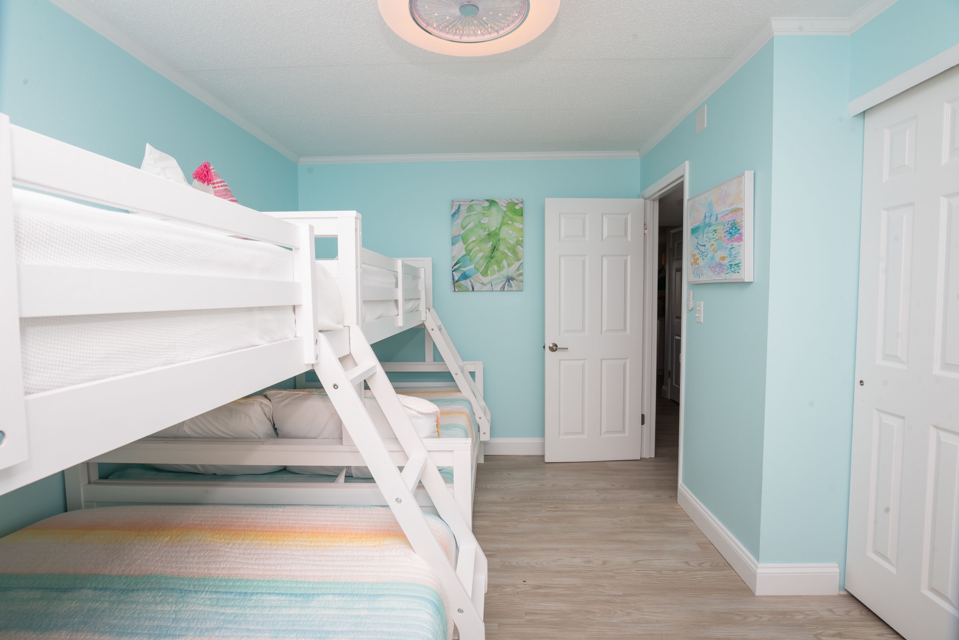 A room with a bunk bed, a door, and a hallway.