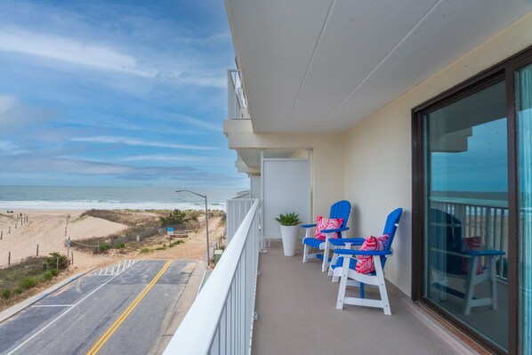 A balcony with a view of the beach, two blue chairs, and a potted plant. - Beautiful Ocean views, Just renovated 2 bedroom 2 bath Condo, 2 parking spots (Ocean City)