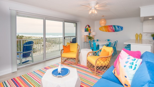 A bright room with a balcony, wicker chairs, a colorful rug, and a ceiling fan. - Beautiful Ocean views, Just renovated 2 bedroom 2 bath Condo, 2 parking spots  (Ocean City)