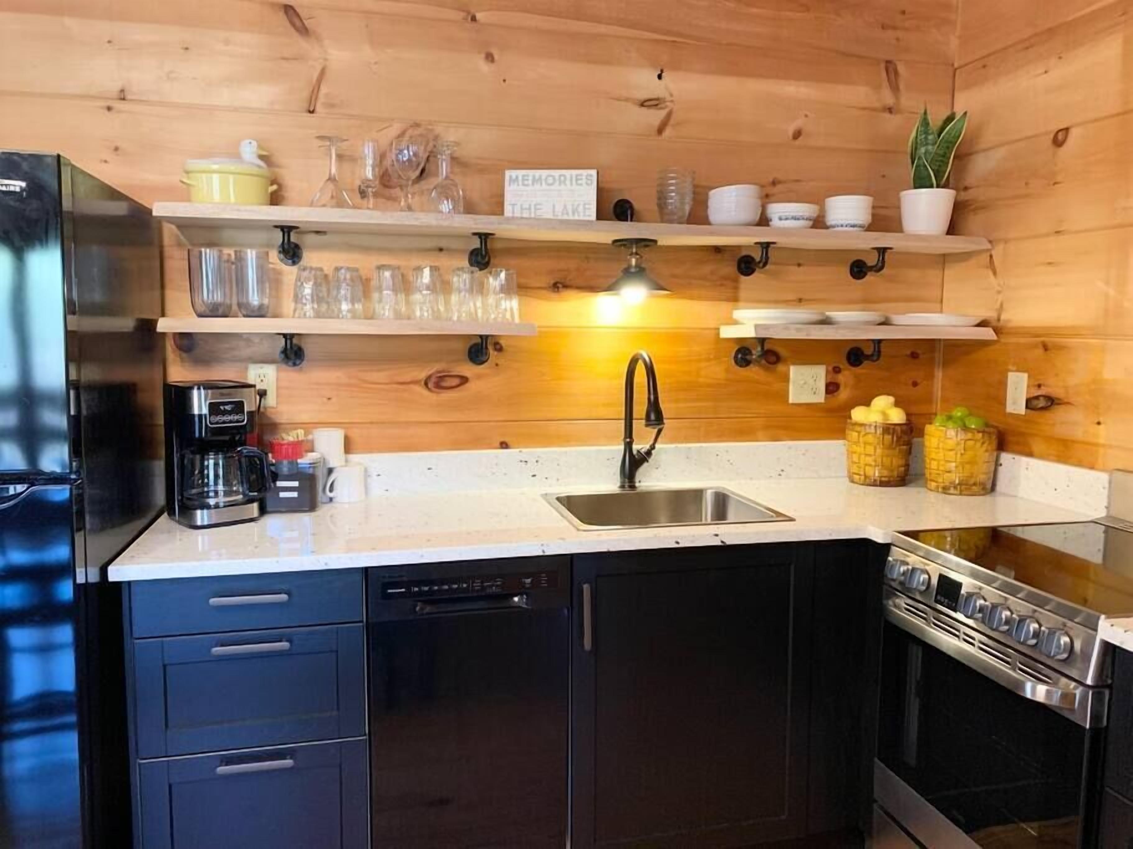 Een kleine keuken met houten wanden, een roestvrijstalen spoelbak, een koffiezetapparaat en een inbouwoven.