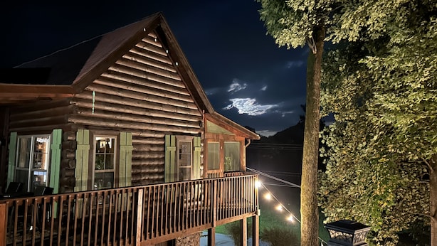 Una baita di legno con un balcone e luci a stringa.
