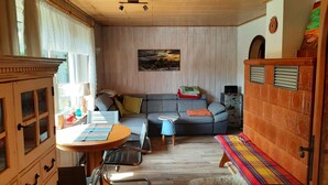 A cozy living room with a sofa, a small table, and a chair. There is a window with curtains, a painting on the wall, and a wooden cabinet. - Harzglück Albertine 505 (Güntersberge)