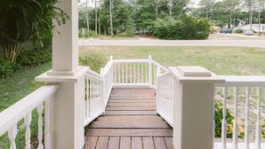 A wooden deck with white railings leading to a grassy area.