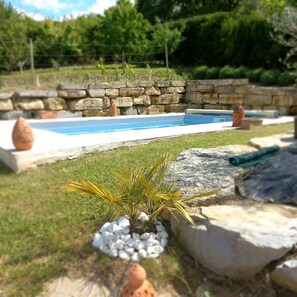 A swimming pool with a stone wall and plants around it. - MAISON DES LAVANDES WITH PRIVATE, NOT OVERLOOKED SWIMMING POOL (Montcuq-en-Quercy-Blanc)