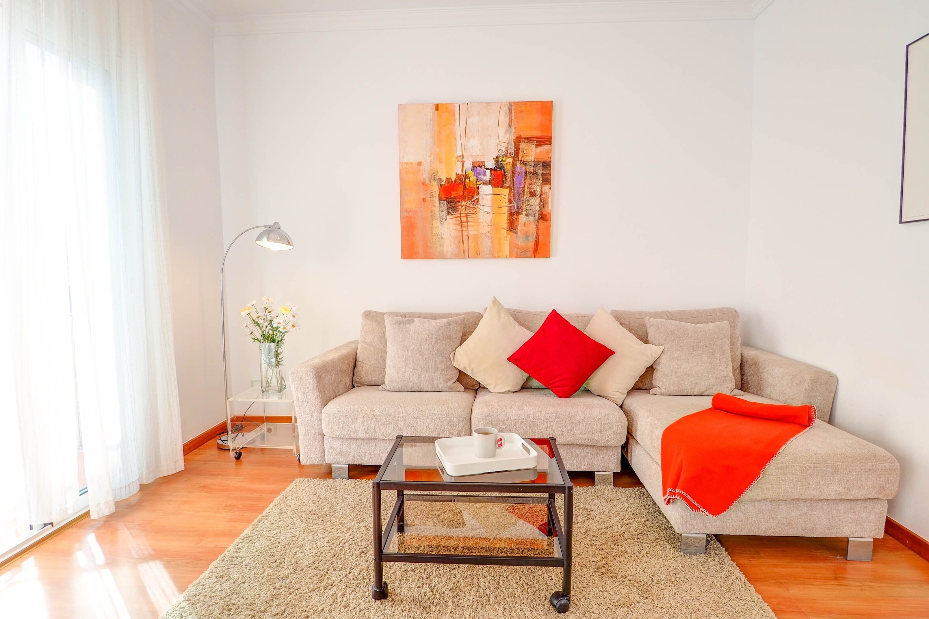 Un salon avec un canapé, une table basse, une lampe et un tableau au mur.