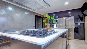 A modern kitchen with a central island, stainless steel appliances, and a potted plant. - Villa Nirvana by Hello Homes Sitges (Sitges)