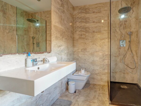A modern bathroom with a large white sink, a mirror, a shower with a handheld showerhead, and a toilet. - Villa Nirvana by Hello Homes Sitges (Sitges)