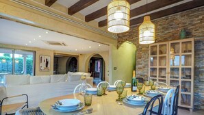 A dining area with a round table set for four, surrounded by wicker chairs. - Villa Nirvana by Hello Homes Sitges (Sitges)
