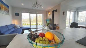 Una sala de estar moderna con un sofá azul, una mesa de comedor con una cesta de fruta y una chimenea.