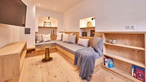 Una habitación acogedora con un banco de madera, una mesa redonda y estantes con libros y objetos decorativos.