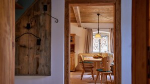 Un interior de madera con zona de comedor, vigas de techo de madera y una lámpara colgante.