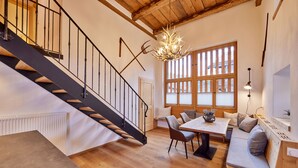 Um interior moderno com escada de madeira, área de refeições e sala de estar com vista para o exterior.