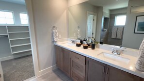 A modern bathroom with a large mirror, two sinks, and a walk-in closet with shelves. - Cool, Clean And Cozy Villa In The Heart of Vicksburg (Vicksburg)