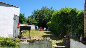 Un patio con césped artificial verde, un muro de hormigón y un banco de madera.